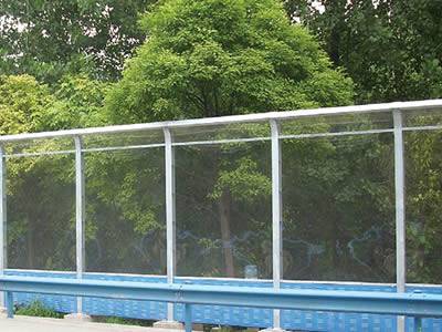 Acrylic sound barrier exists between trees and roads.